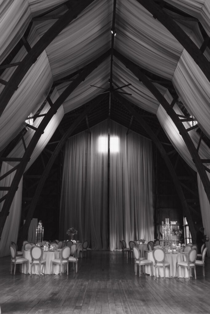 Elegant barn reception space at The Wells Estate in Avon, New York, featuring tall ceilings, soft candlelight, and refined decor
