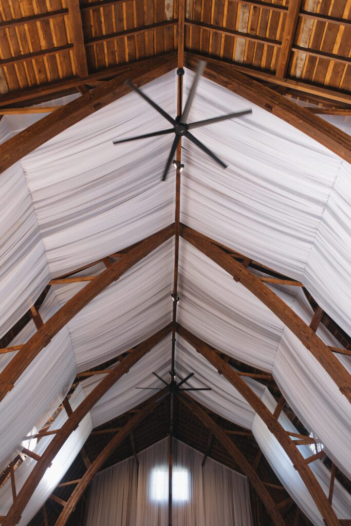Elegant barn reception space at The Wells Estate in Avon, New York, featuring tall ceilings, soft candlelight, and refined decor